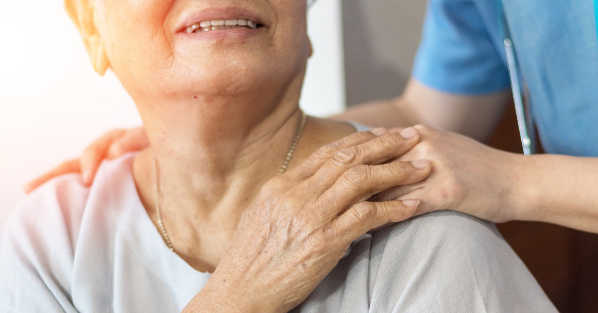 Hymyilevä ikääntynyt pitää hoitajaa kädestä. 